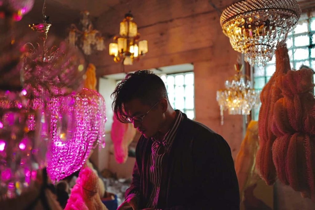 Artist in an interior of chandeliers and coloured light