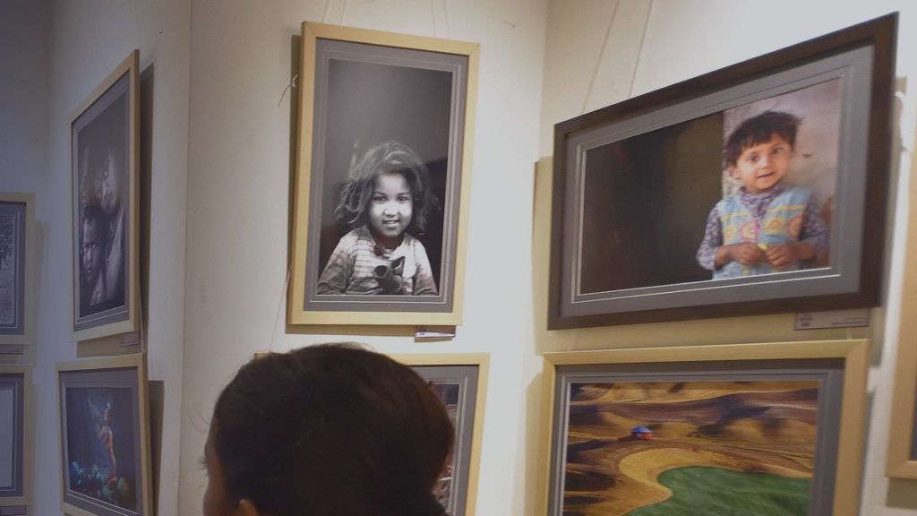 Visitors look at framed photographs at an exhibition