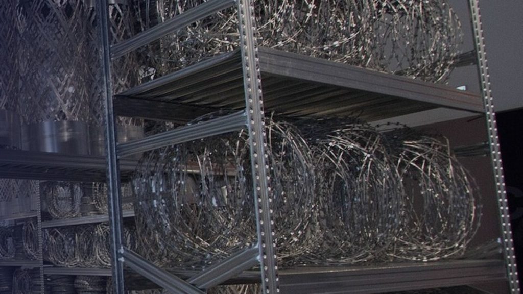 An installation of metal shelving and coiled wire in an exhibition space
