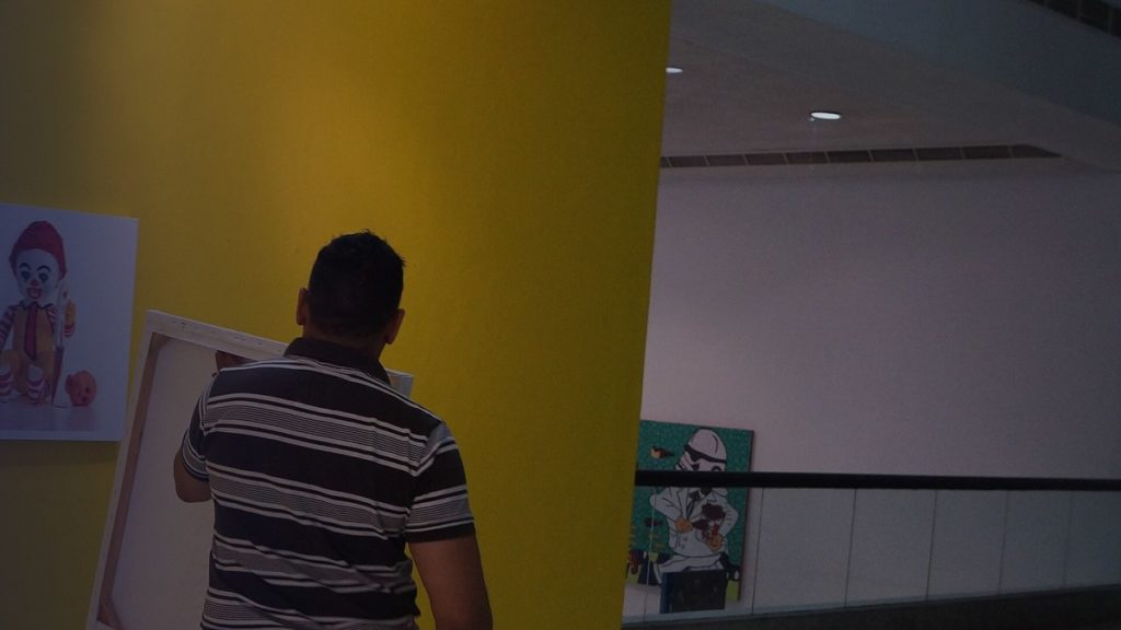 An artist hangs works on a gallery wall before an exhibition