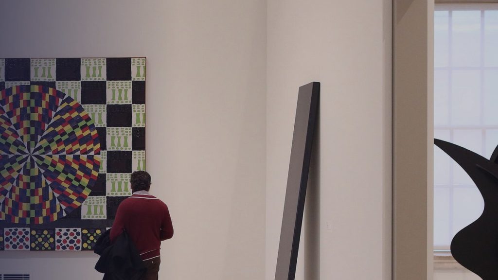 A visitor looks at a large geometric painting in a museum